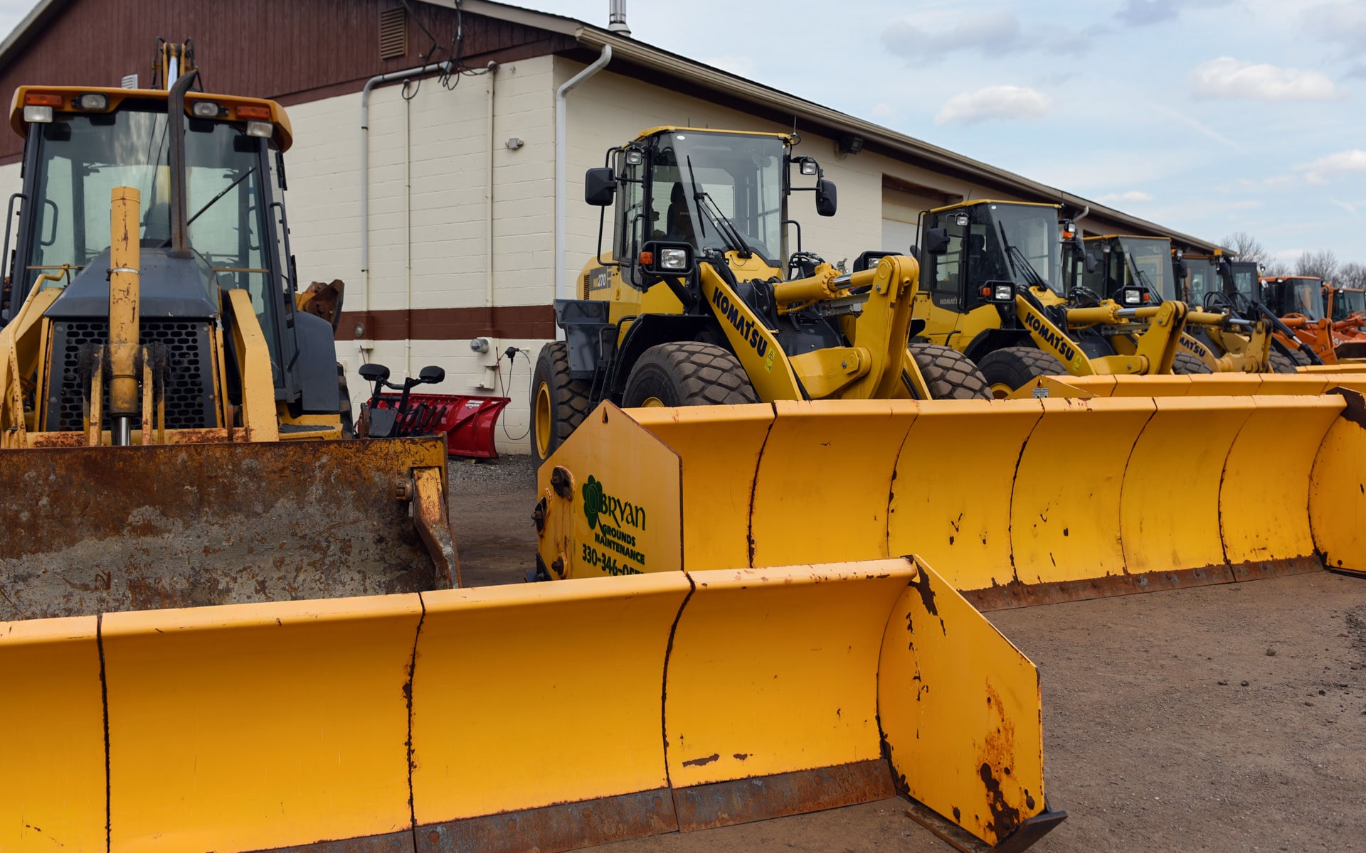 Wheel loaders and backhoes fitted with plow blades at the O'Bryan yard